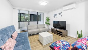 Een moderne woonkamer met een bank, een voetenbankje en een flatscreen televisie.