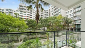 Een modern appartementencomplex met meerdere balkons, weelderige begroeiing en een helder uitzicht op de omliggende gebouwen.