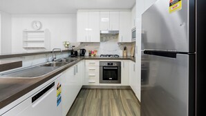 Een moderne keuken met witte kasten, roestvrijstalen apparatuur, een inbouwoven en een magnetron.