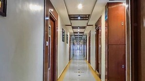 Un pasillo largo y estrecho de hotel con puertas a ambos lados, suelo de baldosas y techo con diseño.