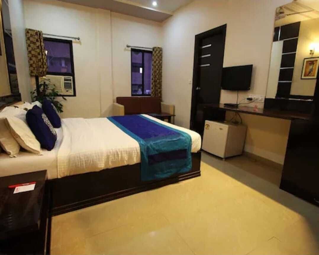 A hotel room with a bed, a desk, a television, and a window.