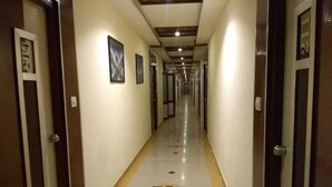 Un pasillo largo y estrecho con puertas a ambos lados, que conduce a habitaciones individuales.
