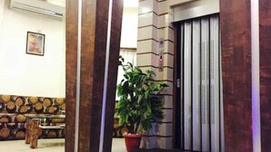 Un vestíbulo con un banco de madera, una planta en maceta y una puerta de ascensor cerrada.