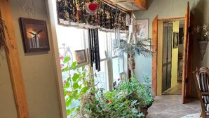 Ein gemütliches Zimmer mit Steinboden, Holzbalkendecke und einem Fenster mit Blick auf Grün.