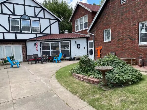 Een woonhuis met een garage, een terras met tuinmeubilair en een keurig onderhouden tuin.