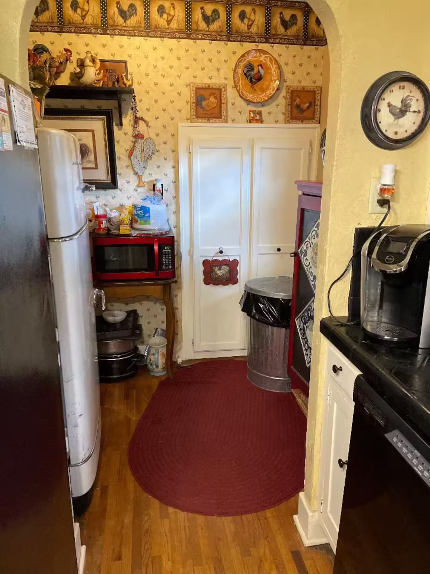 A compact kitchen with a refrigerator, microwave, coffee maker, and a trash can.