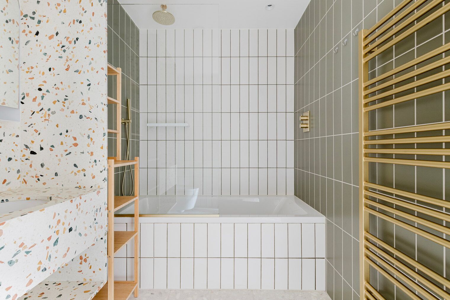 A modern bathroom with a freestanding bathtub, a showerhead, and a wooden shelf unit.