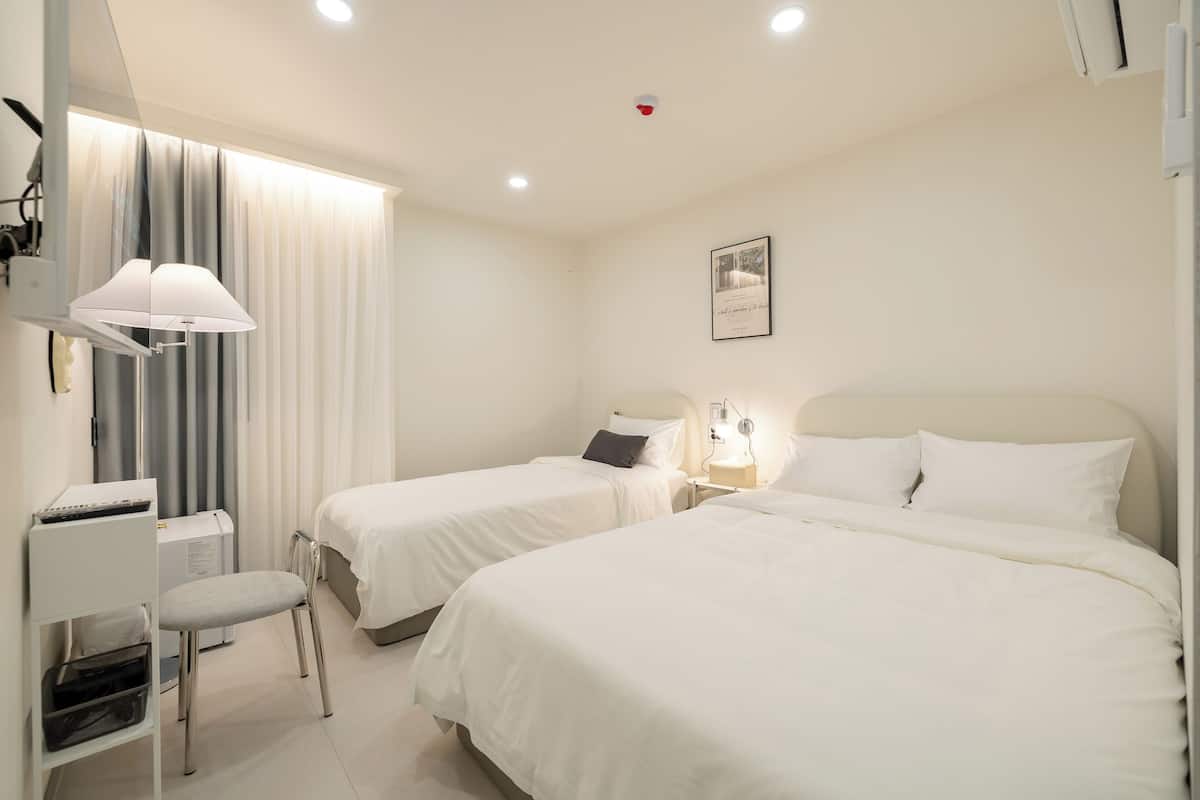 Een hotelkamer met twee bedden, een bureau met een stoel, een lamp en een ingelijst schilderij aan de muur.
