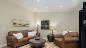 A living room with two brown leather sofas, a round coffee table, a rug, and two wall-mounted lamps. - Serene Table Rock Cabin - Close to Lake & SDC!!! (Kimberling City)