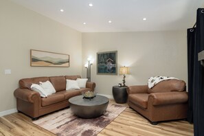 A living room with two brown leather sofas, a round coffee table, a rug, and two wall-mounted lamps. - Serene Table Rock Cabin - Close to Lake & SDC!!! (Kimberling City)