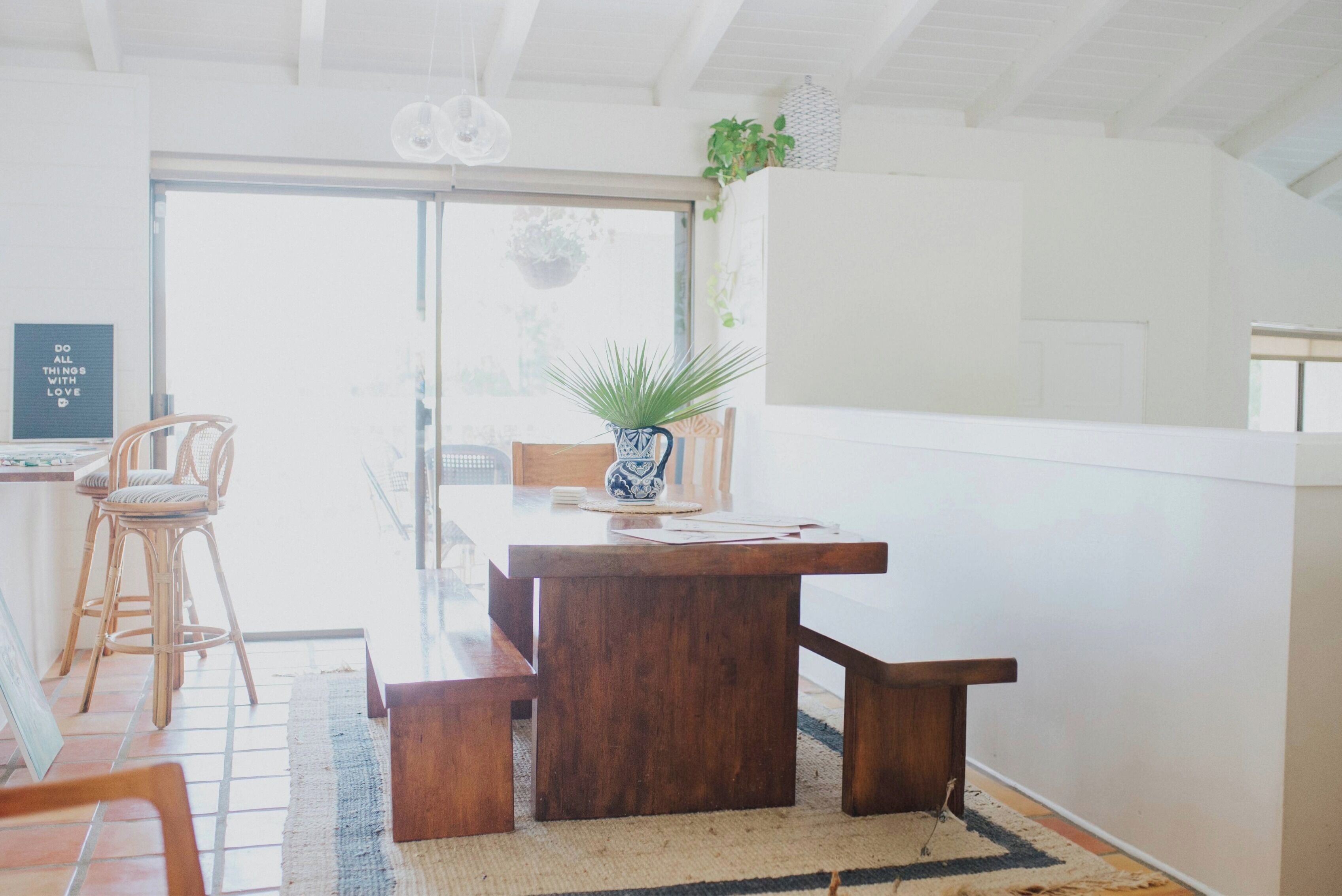 Uma sala de jantar com mesa de madeira, cadeiras e um vaso com planta.