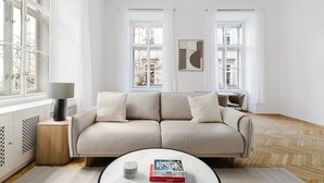 En moderne stue med en beige sofa, et rundt sofabord med bøger og en lampe.