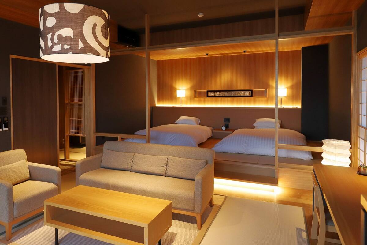 A hotel room with a sofa, a coffee table, a bed, and a lamp.