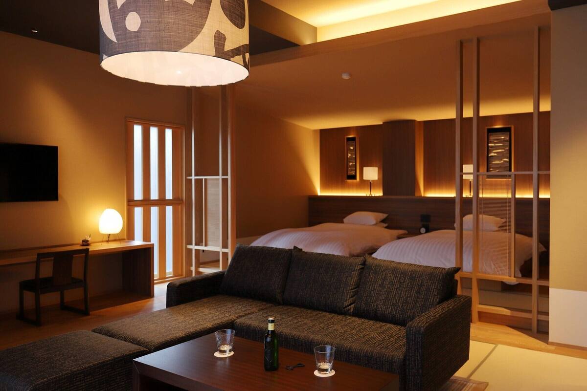A hotel room with a sofa, a dining table, a bed, and a TV.