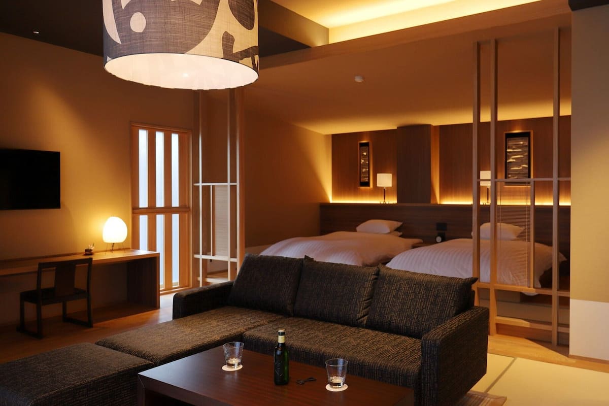 A hotel room with a sofa, a dining table, a bed, and a TV.