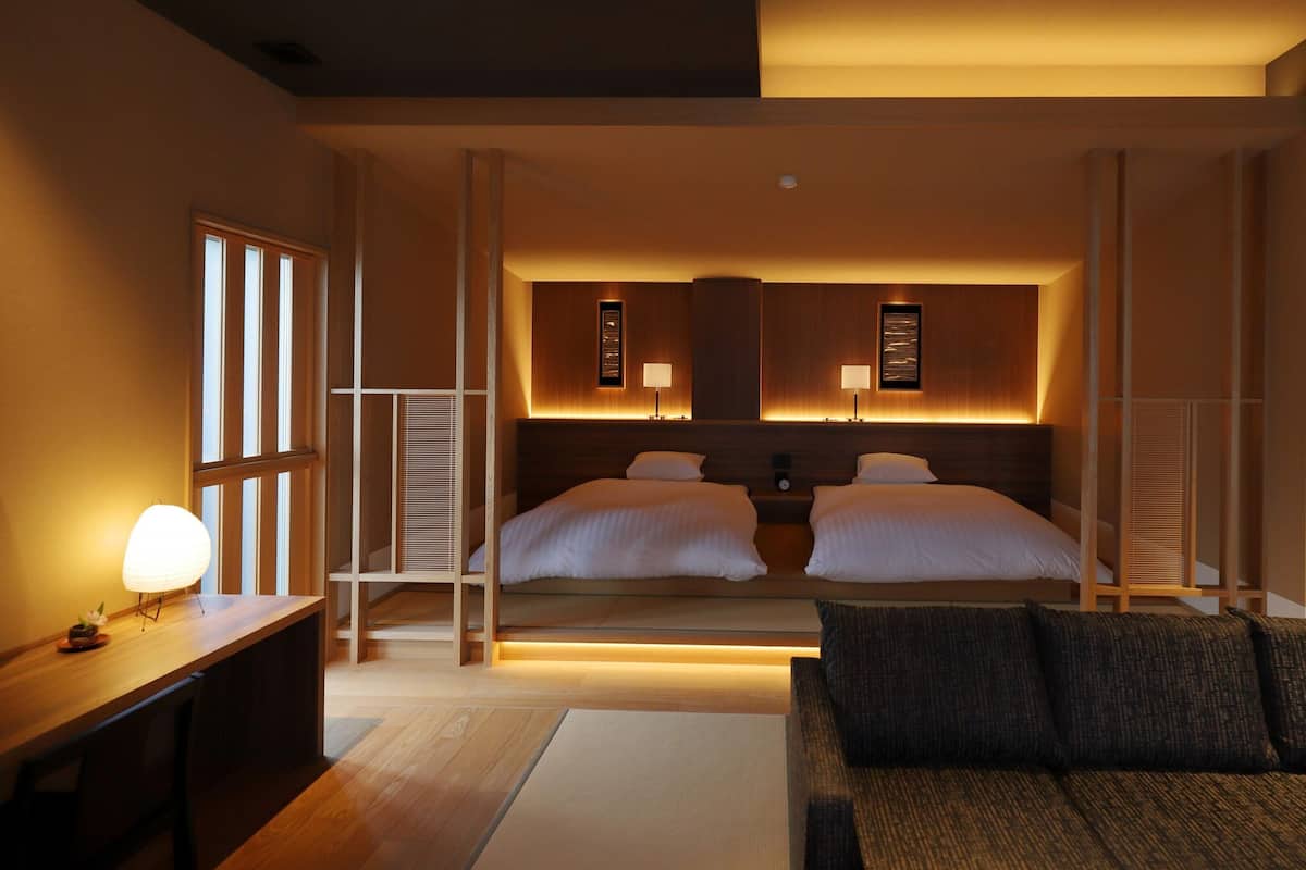 A hotel room with a bed, bedside tables, a sofa, and a view of the outside.