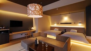 Una habitación de hotel moderna con sofá, dos camas, televisor, escritorio y lámpara.