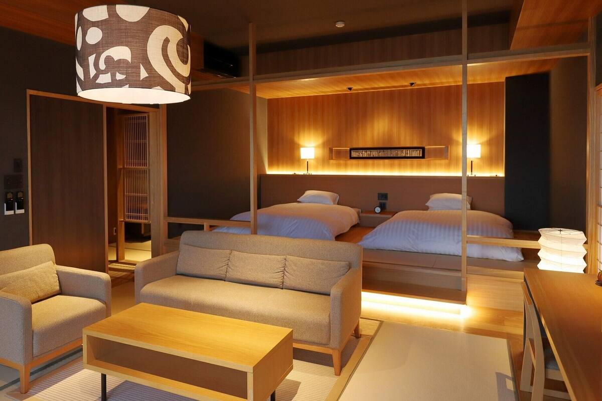 A modern hotel room with a sofa, a coffee table, a bed, and a large decorative lamp.
