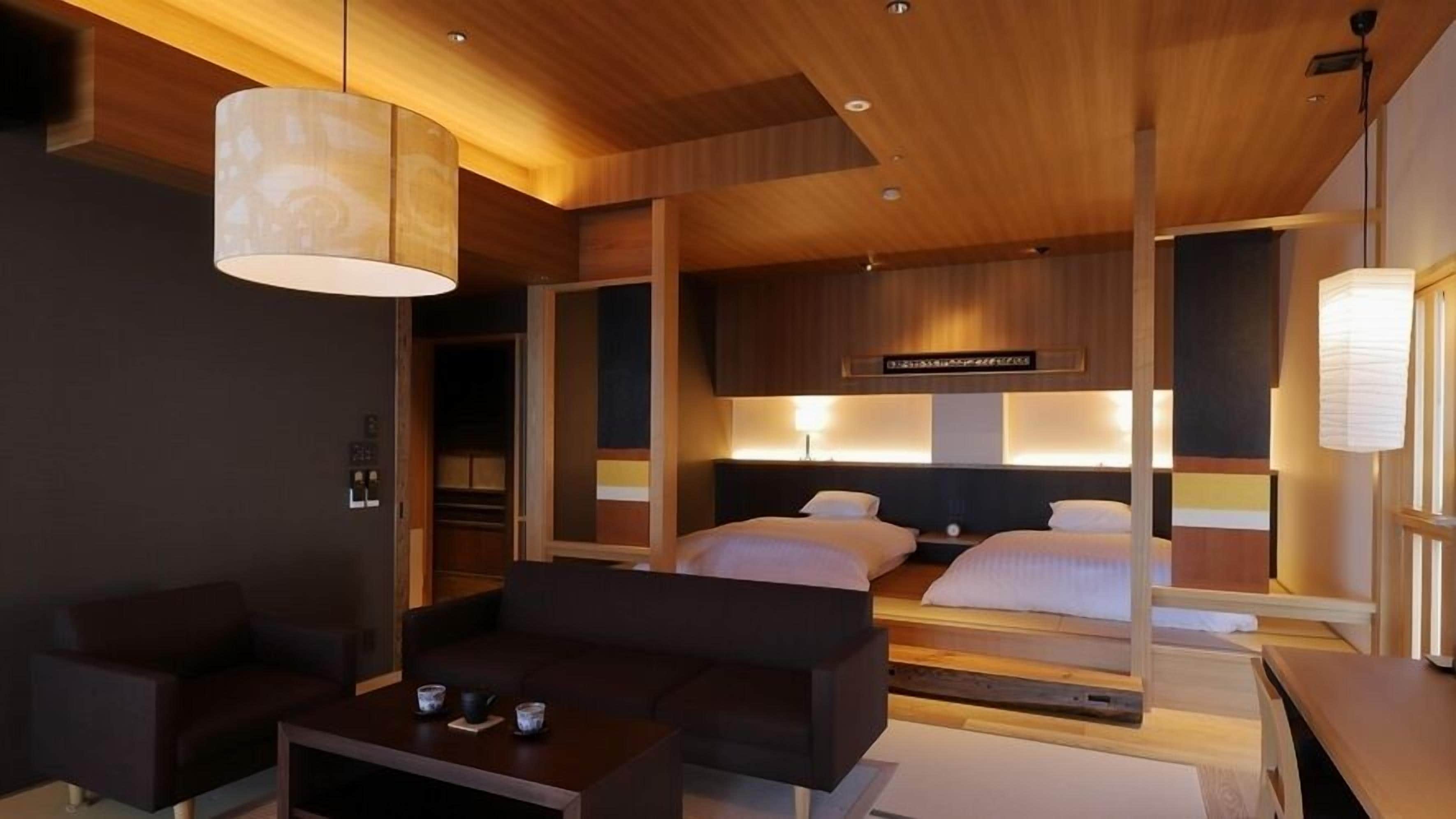 Quarto de hotel moderno com uma cama grande, um sofá, uma mesa de centro e um closet espaçoso.