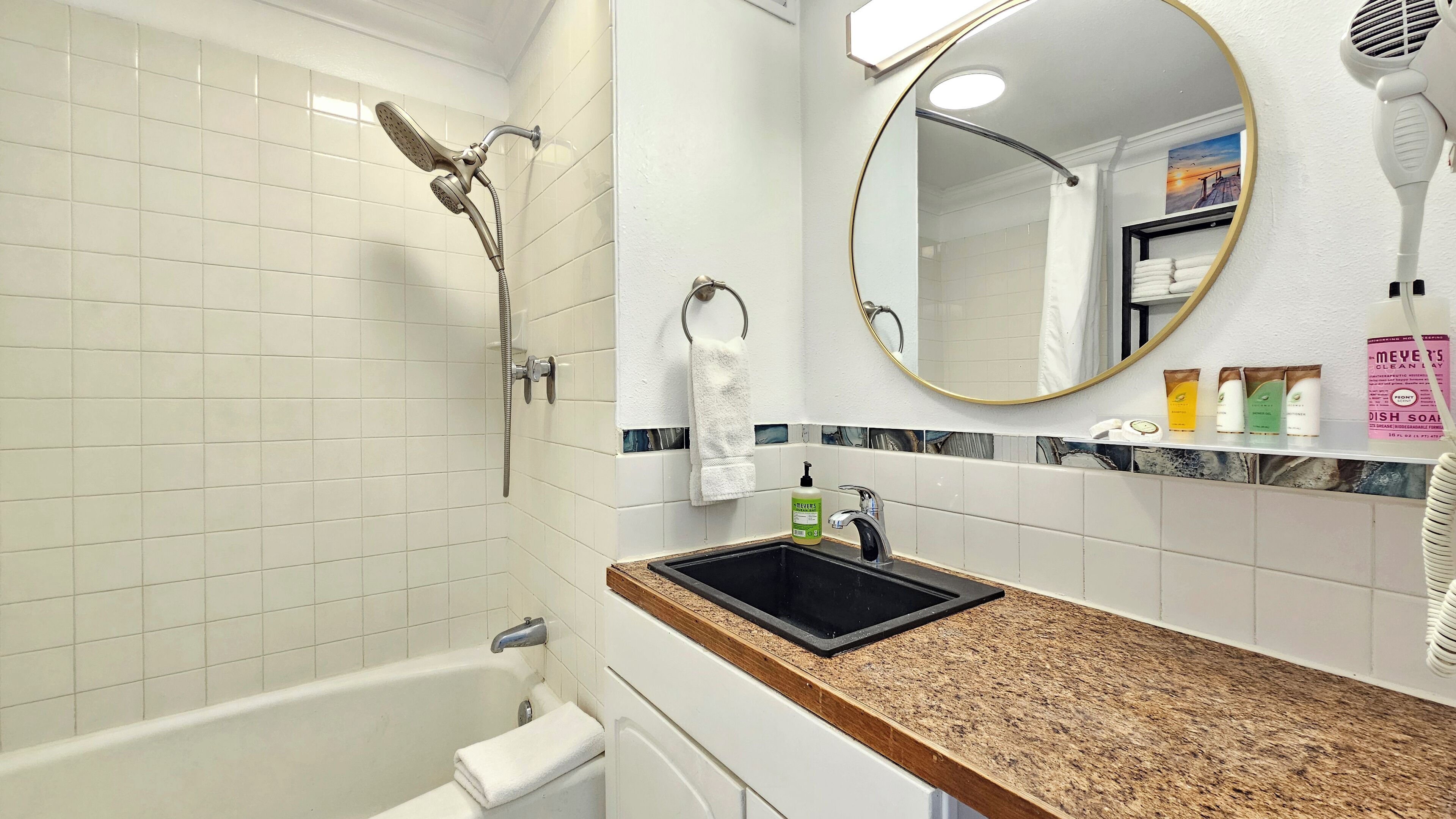 Une salle de bain avec une baignoire, un lavabo, un miroir et une pomme de douche.