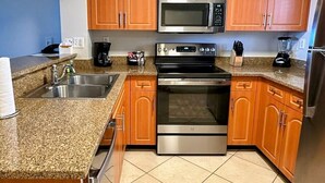 Una cucina con mobili in legno, un forno a microonde in acciaio inox, un fornello e una macchina per il caffè.