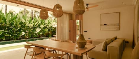 A modern dining area with a wooden table and chairs, a large vase, and hanging wicker lamps.
