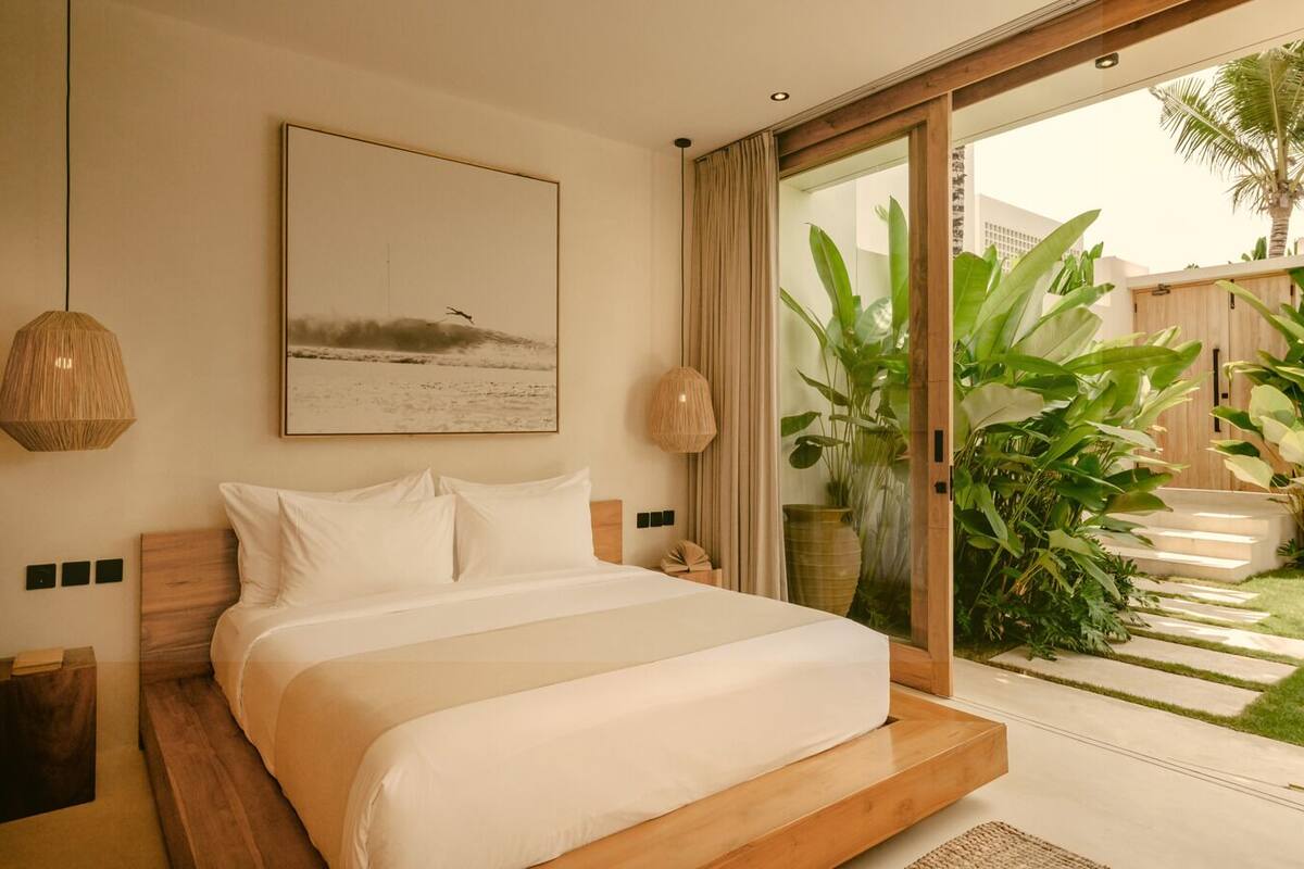 Ein Schlafzimmer mit einem großen Bett, Blick auf einen Garten und einem Gemälde an der Wand.