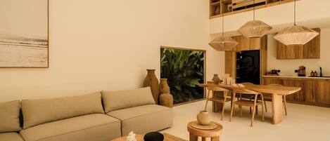 A modern living room with a sofa, coffee table, and dining area.