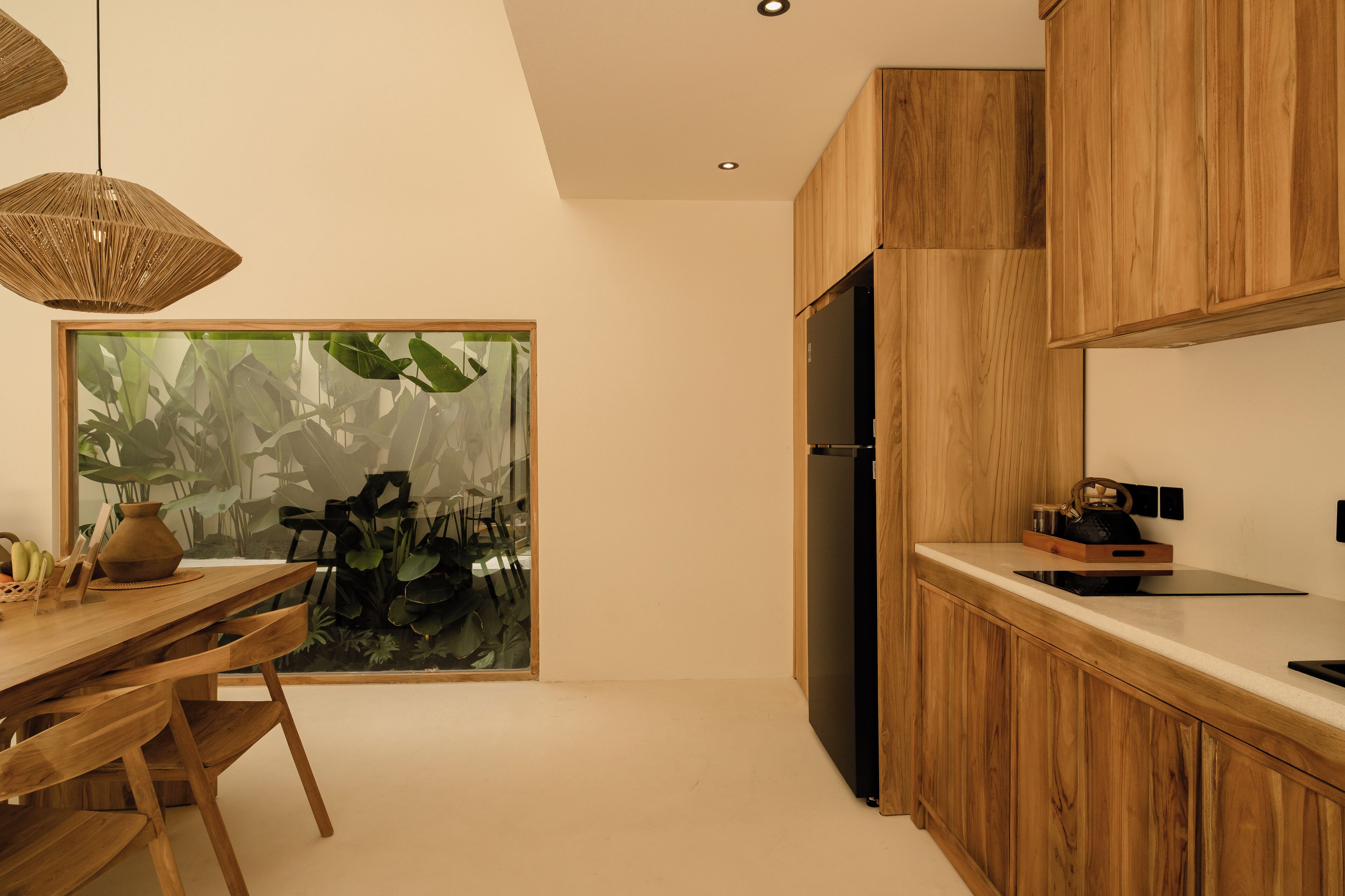 A modern kitchen with wooden cabinets, a black refrigerator, and a dining area with a wooden table and chairs.