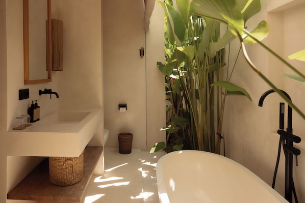A modern bathroom with a freestanding bathtub, a wooden shelf, a sink, and a mirror. - COZ Bali Boutique Villas (Uluwatu)