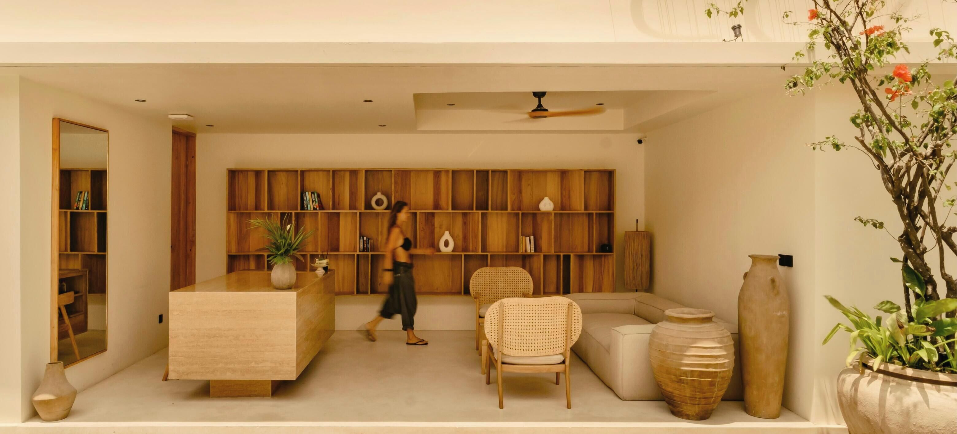 A modern living room with a wooden bookshelf, a sofa, a chair, and a large vase.