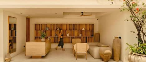 A modern living room with a wooden bookshelf, a sofa, a chair, and a large vase.