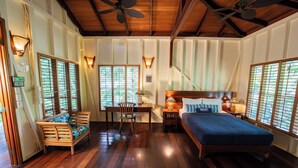 A room with a bed, a desk, and a chair. There are windows with blinds and a ceiling fan. - La Pina Casita at Bluff Beach Retreat (Isla Colon)