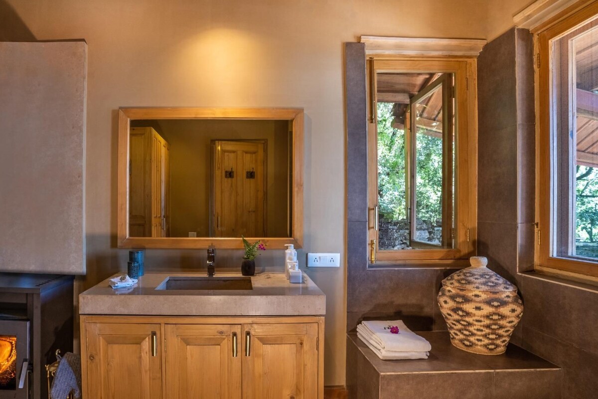 A bathroom with a wooden cabinet, a sink, a mirror, a window, and a fireplace.