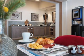A breakfast setting with croissants, scrambled eggs, and bacon on a table, a coffee machine, and a water dispenser. - MGM Hôtels et Résidences - Hotel Alhena (Magland)