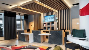 A modern reception area with a TV, seating, and a patterned carpet. - MGM Hôtels et Résidences - Hotel Alhena (Magland)