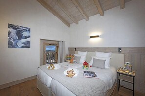 A bedroom with a bed, a nightstand, a window with a view, and a painting on the wall. - MGM Hôtels et Résidences - Hameau De L'ours (Manigod)