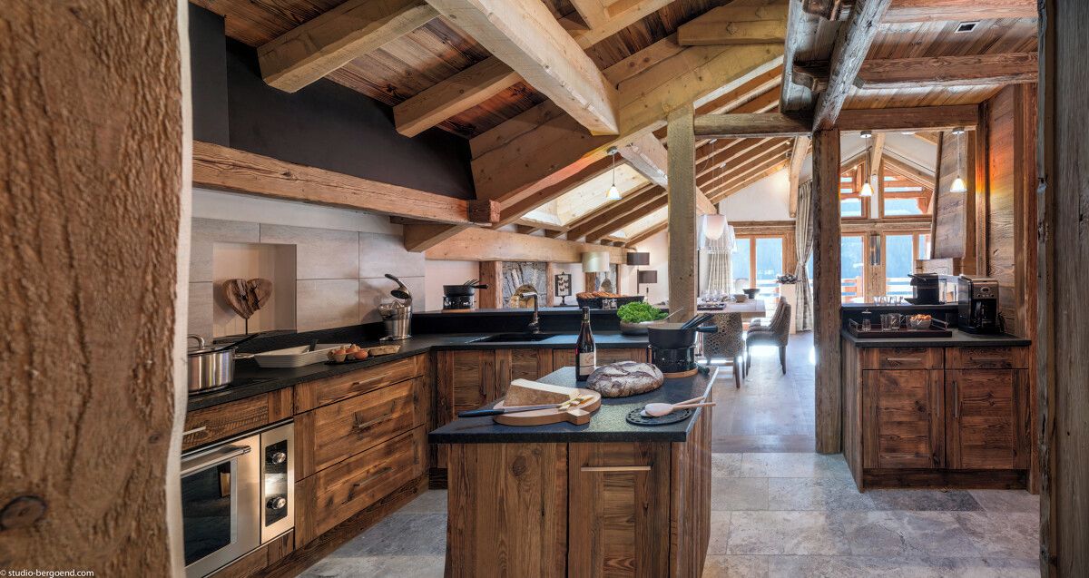 Cocina amplia con alacenas de madera y una isla central, que cuenta con horno empotrado y un ventanal para luz natural.
