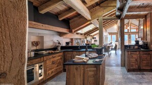 Cocina amplia con alacenas de madera y una isla central, que cuenta con horno empotrado y un ventanal para luz natural.