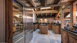 Una cocina moderna con vigas de madera, un refrigerador de acero inoxidable y una isla central.