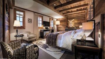 A cozy log cabin-style bedroom with a large bed, a desk, and a chair.