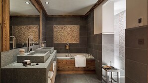 Un baño moderno con tocador de madera, una bañera independiente y un revestimiento de mosaicos.