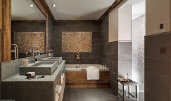 A modern bathroom with a wooden vanity, a freestanding bathtub, and a mosaic wall.