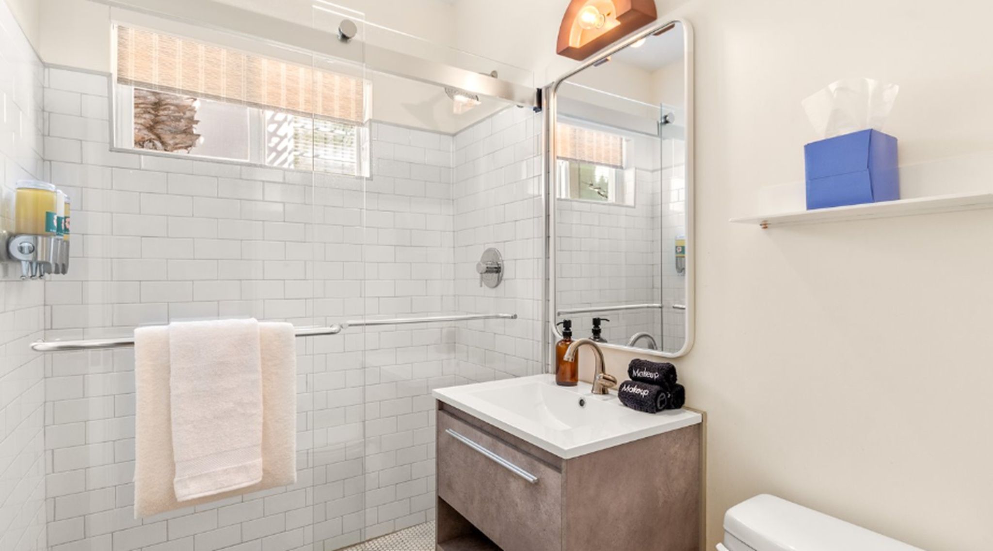 A modern bathroom with a walk-in shower, a white sink, and a large mirror.