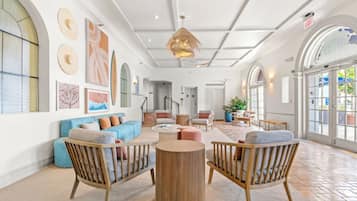 A spacious lobby with a high ceiling, large windows, and a mix of seating areas including sofas and chairs.