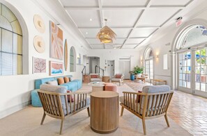 A spacious lobby with a high ceiling, large windows, and a mix of seating areas including sofas and chairs. - Aloha Fridays Miami Beach (Bal Harbour)