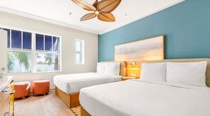 A hotel room with two beds, a desk, and a chair. There is a window with a view of palm trees and a building. - Aloha Fridays Miami Beach (Bal Harbour)