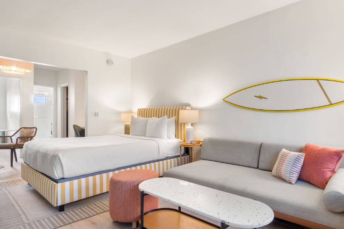 A hotel room with a bed, a sofa, a small table, and a chair.