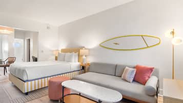 Quarto de hotel com cama, sofá, mesa pequena e cadeira.