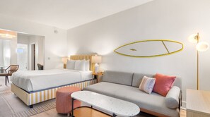 A hotel room with a bed, a sofa, a small table, and a chair. - Aloha Fridays Miami Beach (Bal Harbour)